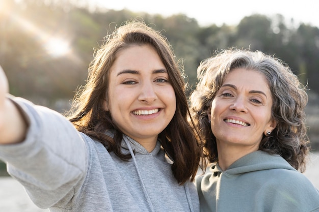 Uśmiechnięta córka robi selfie z matką na zewnątrz