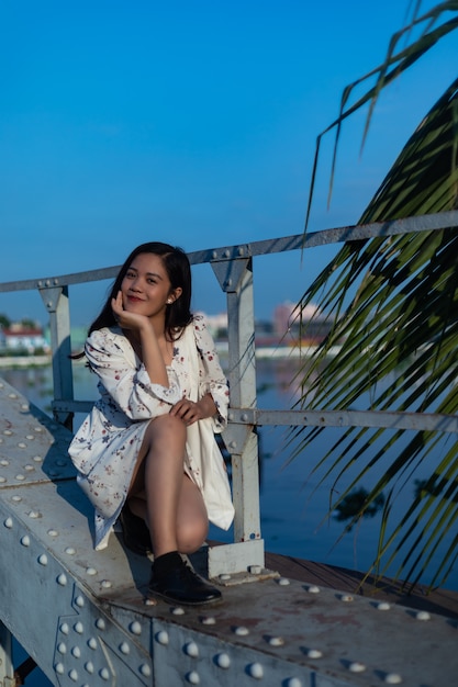 Uśmiechnięta Czarnowłosa Wietnamska Dziewczyna Siedzi Na Moście