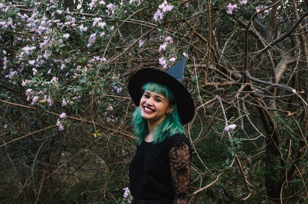 Uśmiechnięta czarownica na drzewie z kwiatami