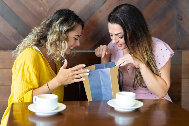 Uśmiechnięta dama pokazuje zakup przyjaciel w kawiarni