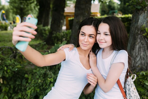 Uśmiechnięta dziewcząt przytulanie biorąc selfie