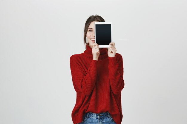 Uśmiechnięta dziewczyna reklamuje aplikację, pokazuje ekran cyfrowego tabletu