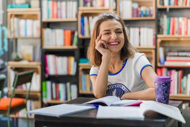 Uśmiechnięta dziewczyna siedzi przy stole z notebooków