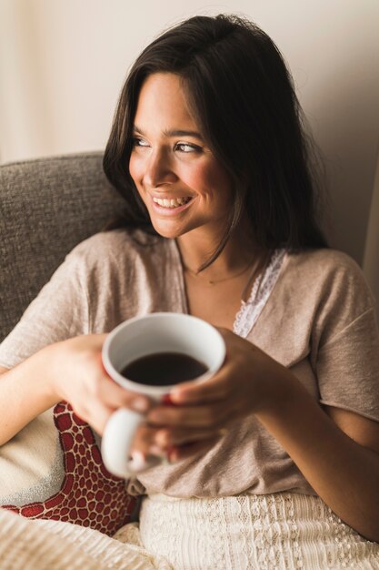 Uśmiechnięta dziewczyna trzyma filiżankę kawy