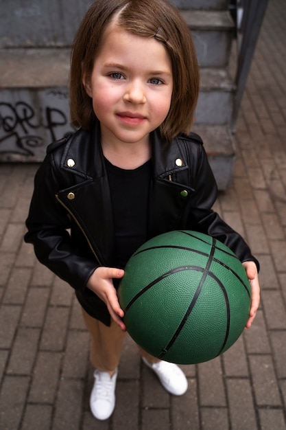Bezpłatne zdjęcie uśmiechnięta dziewczyna trzyma piłkę pod wysokim kątem