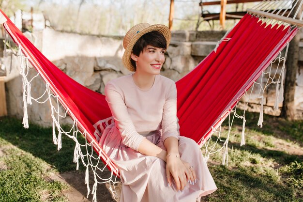 Bezpłatne zdjęcie uśmiechnięta dziewczyna z eleganckim manicure na sobie długą sukienkę retro odpoczynek na świeżym powietrzu w słoneczny dzień