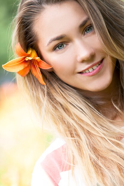 Uśmiechnięta dziewczyna z leluja kwiatem we włosy