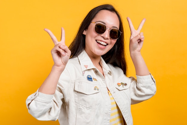 Bezpłatne zdjęcie uśmiechnięta dziewczyna z okularami przeciwsłonecznymi na żółtym tle