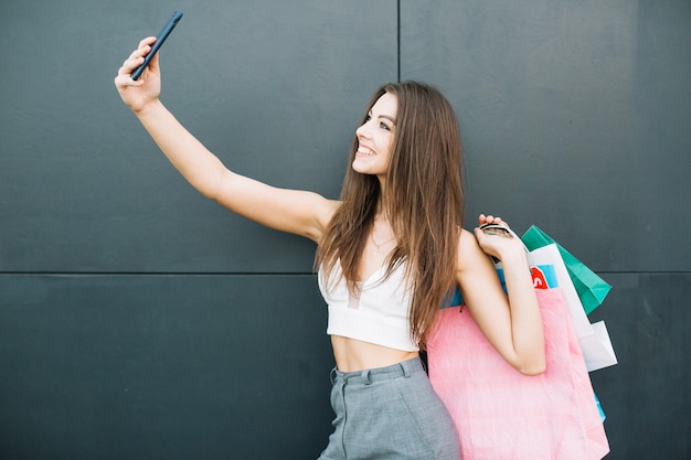 Uśmiechnięta dziewczyna z torby podejmowania selfie