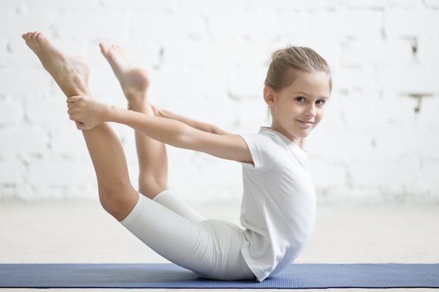 Uśmiechnięta Dziewczynka W Dhanurasana Stwarzają, Białe Tło Studyjny