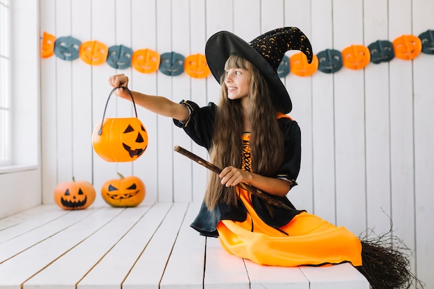 Uśmiechnięta Halloweenowa czarownica trzyma Jack-O-Lantern