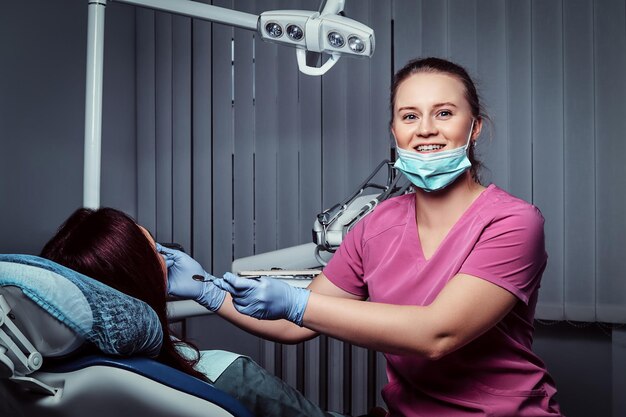 Uśmiechnięta Kobieta Dentysta Leczy Pacjentkę Siedzącą Na Fotelu Dentystycznym W Klinice.