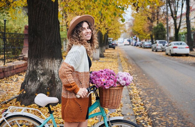 Uśmiechnięta kobieta jedzie na rowerze w centrum miasta lub jesiennym parku
