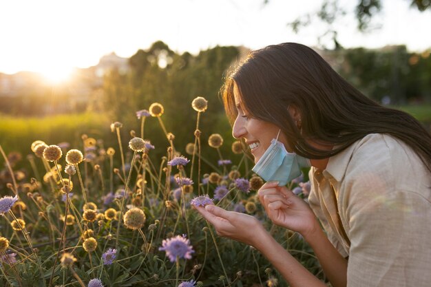 Uśmiechnięta kobieta pachnąca kwiatami widok z boku