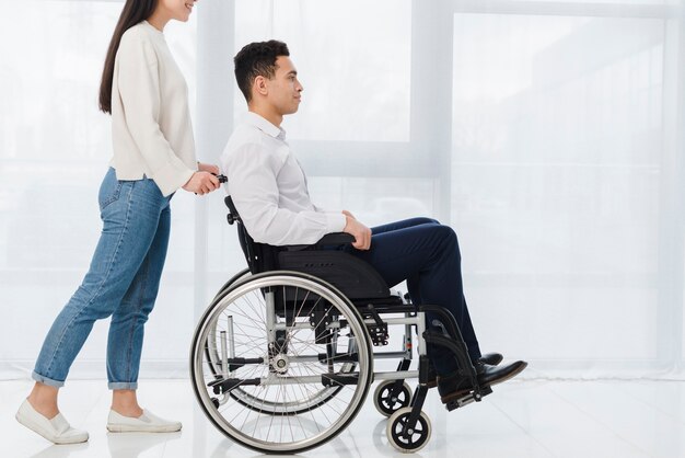 Uśmiechnięta kobieta pcha młody człowiek siedzi na wózku inwalidzkim