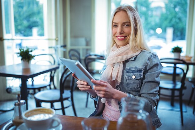 Uśmiechnięta kobieta przy użyciu cyfrowego tabletu w kawiarni