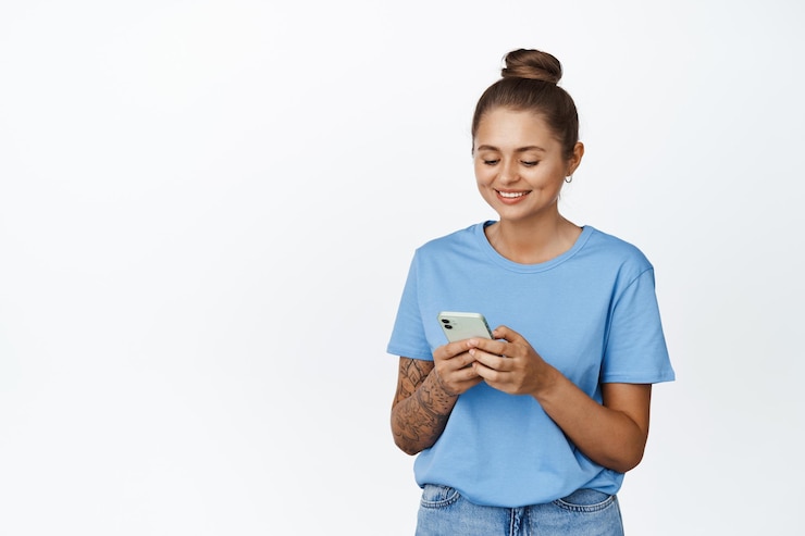 Bezpłatny plik Zdjęcie uśmiechnięta kobieta przy użyciu telefonu komórkowego, patrząc na ekran. koncepcja rezerwacji taksówki, aplikacji i technologii