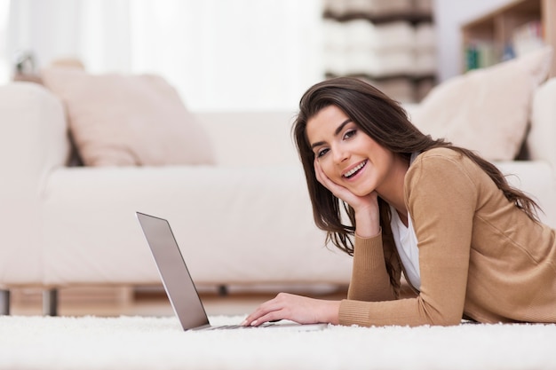 Uśmiechnięta kobieta relaksuje w domu z laptopem
