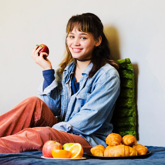Uśmiechnięta kobieta siedzi z jabłkiem