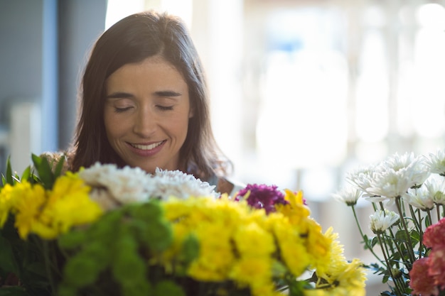Uśmiechnięta kobieta trzyma bukiet z zamkniętymi oczami w kwiaciarni