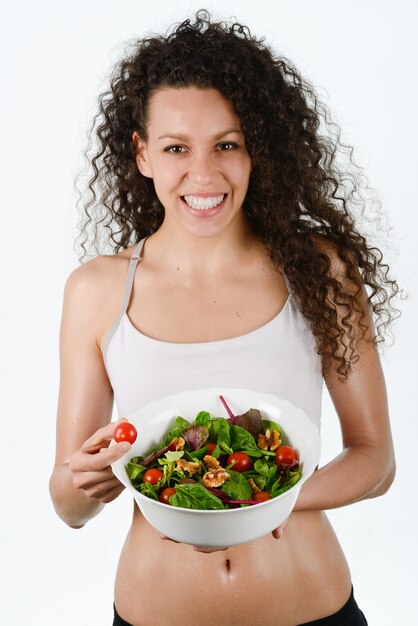 Uśmiechnięta kobieta trzyma cherry pomidorów i sałatki