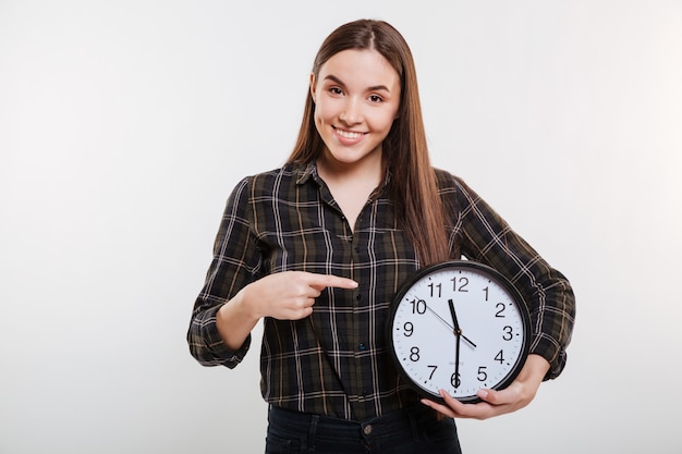 Uśmiechnięta kobieta trzyma zegar w koszula