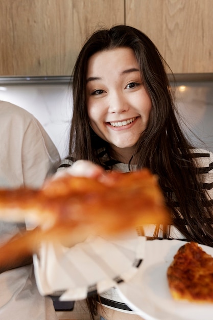 Uśmiechnięta kobieta trzymająca kawałek pizzy
