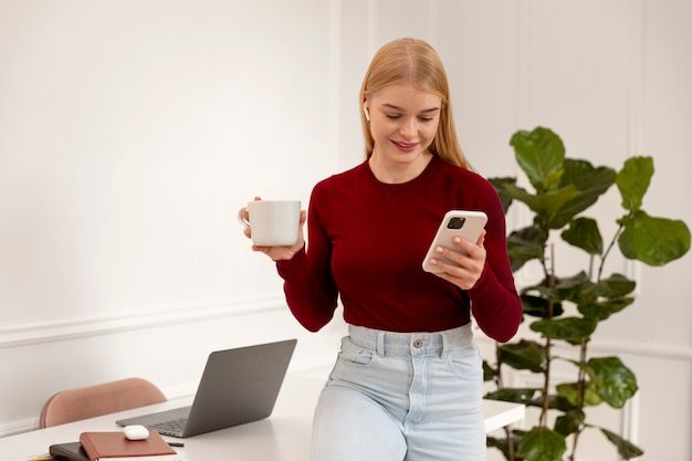 Uśmiechnięta kobieta trzymająca telefon średni strzał