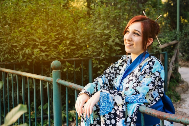 Uśmiechnięta kobieta w kimono w pobliżu ogrodzenia