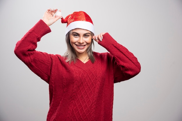 Uśmiechnięta Kobieta W Santa Hat Pozuje Na Szarym Tle.