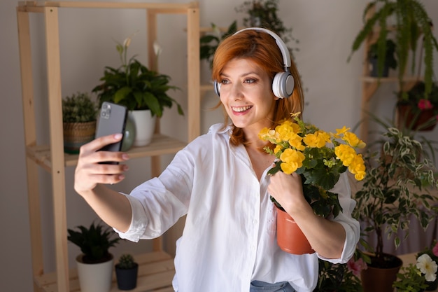 Uśmiechnięta kobieta w średnim ujęciu biorąca selfie