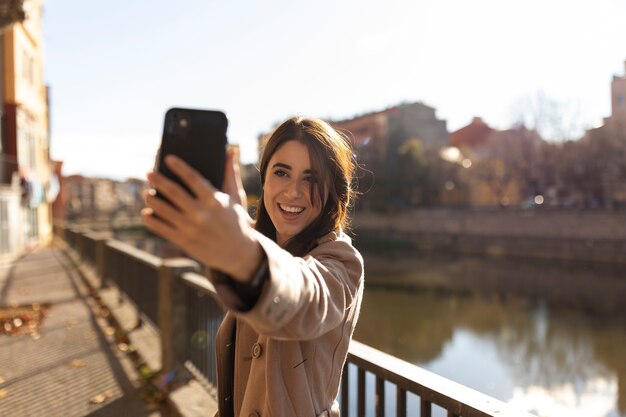 Uśmiechnięta kobieta w średnim ujęciu robi selfie