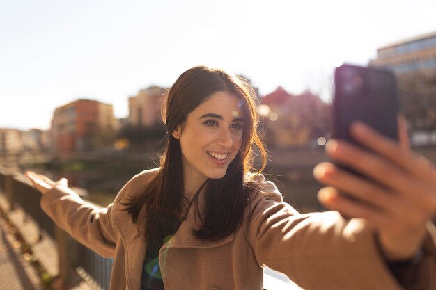 Uśmiechnięta kobieta w średnim ujęciu robi selfie