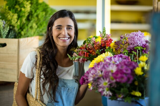 Uśmiechnięta kobieta wybierając kwiaty w kwiaciarni