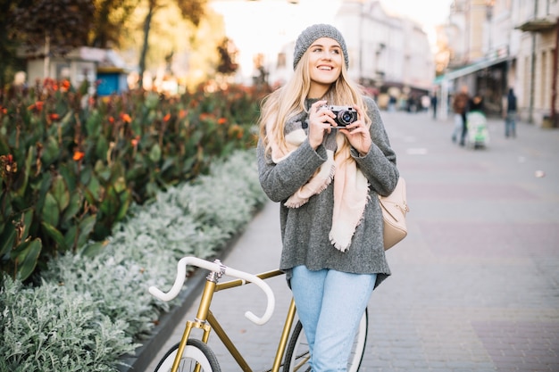 Uśmiechnięta kobieta z kamerą i bicyklem