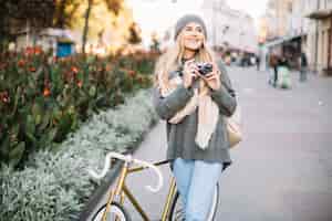 Bezpłatne zdjęcie uśmiechnięta kobieta z kamerą i bicyklem