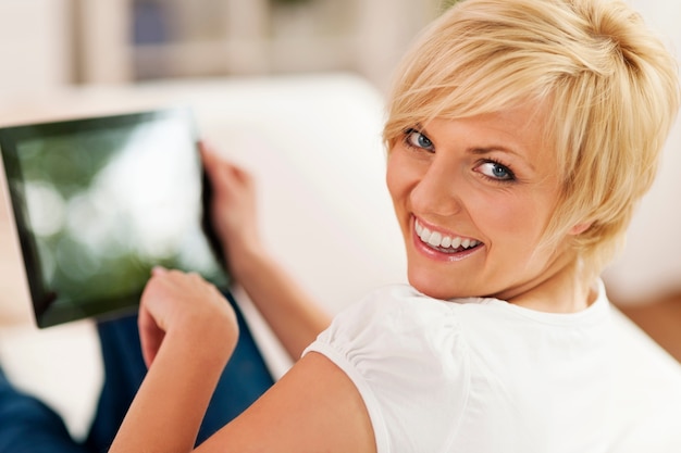 Uśmiechnięta kobieta za pomocą cyfrowego tabletu w domu
