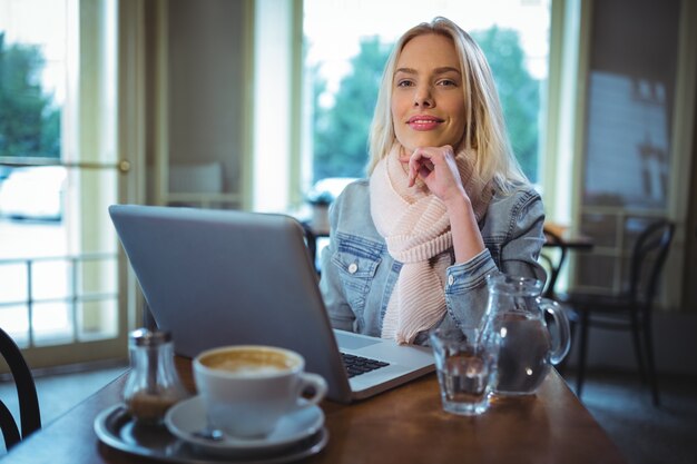 Uśmiechnięta kobieta za pomocą laptopa, kawie