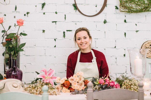 Bezpłatne zdjęcie uśmiechnięta kwiaciarnia przy pracującym miejscem