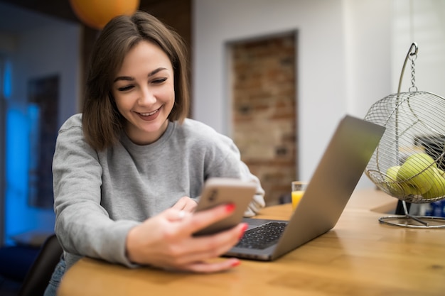 Uśmiechnięta ładna kobieta pracuje w domu na laptopie