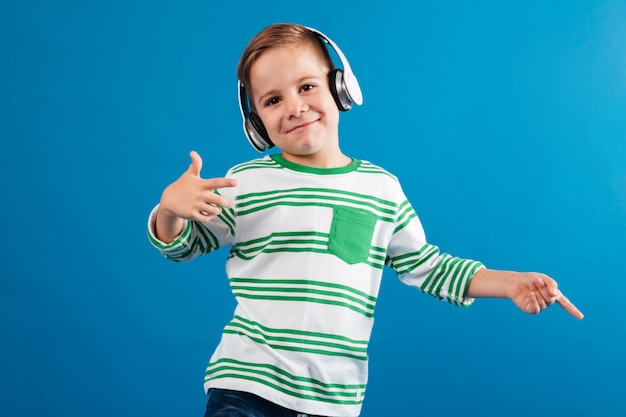 Uśmiechnięta młoda chłopiec słucha muzykę i tana