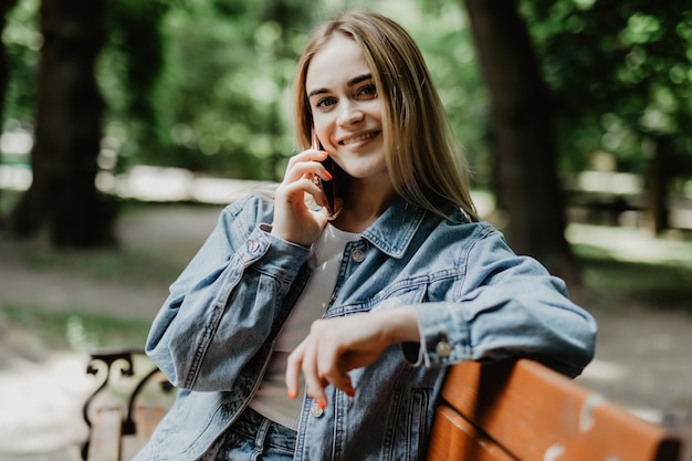 Uśmiechnięta młoda kobieta dzwoni na smartphone na miasto ulicie