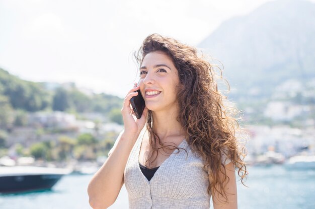 Uśmiechnięta młoda kobieta opowiada na telefonie komórkowym