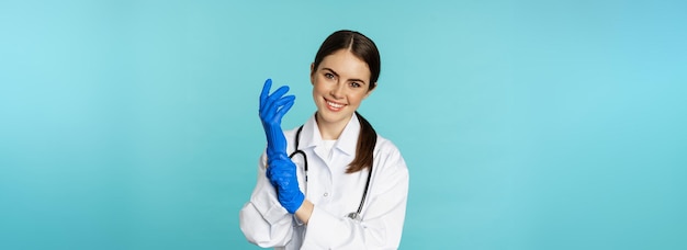 Uśmiechnięta Młoda Kobieta Pracownik Medyczny W Rękawiczkach Do Badania Pacjenta Stojącego W Szpitalnej Klinice Un