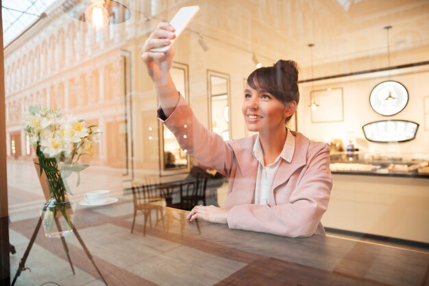 Uśmiechnięta młoda kobieta robi selfie fotografii