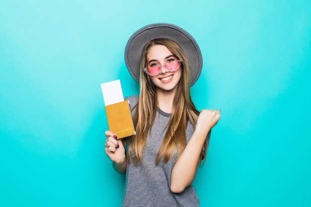 Uśmiechnięta młoda nastoletnia dama trzyma jej dokumenty paszportowe z biletem w dłoniach na białym tle na ścianie zielonego studia