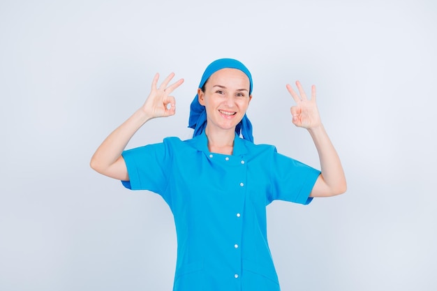 Uśmiechnięta młoda pielęgniarka pokazuje dobre gesty na białym tle