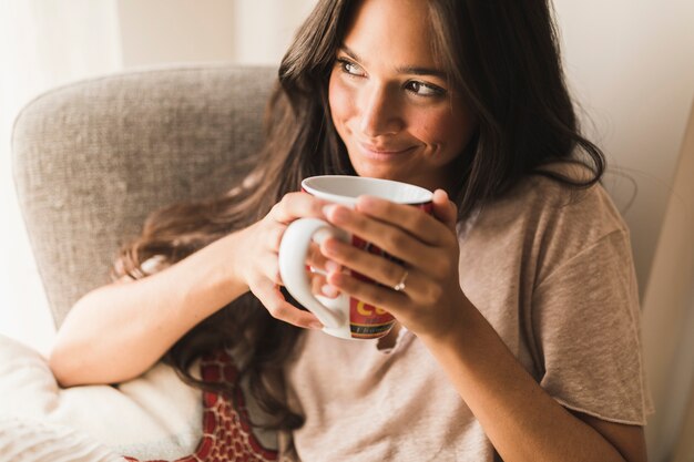 Uśmiechnięta nastoletnia dziewczyna trzyma kawowego kubek