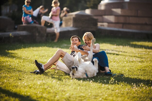 Uśmiechnięta para bawi się ze swoim psem