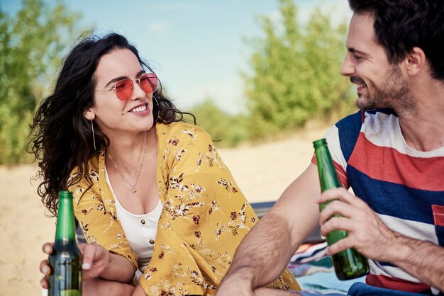 Uśmiechnięta Para Pijąca Zimne Piwo Na Plaży